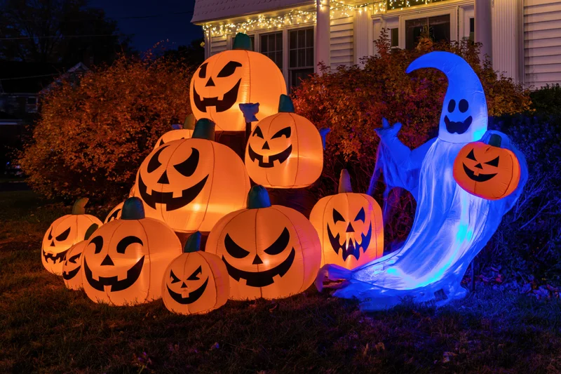 Inflatable halloween pumpkins and ghost glowing on a front lawn at night