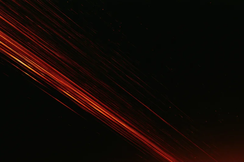 Long-exposure night sky with diagonal streaks of red and orange light from meteors