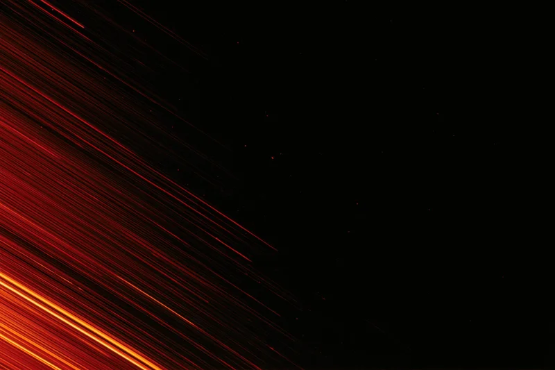 Long-exposure night sky with streaking red and orange meteor trails across dark space