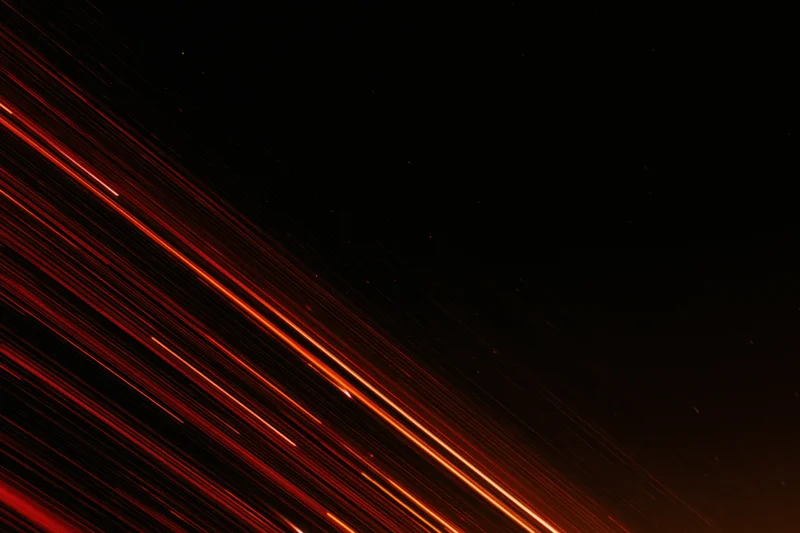Long-exposure night sky with streaking red and orange meteor trails across dark space