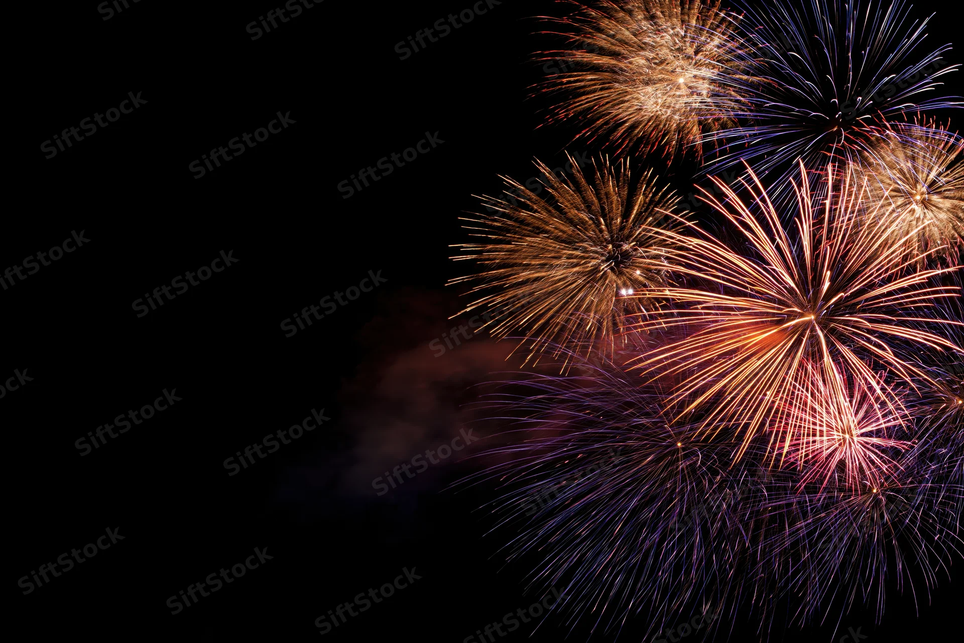 Fireworks bursting in the night sky with vibrant colors and smoke trails