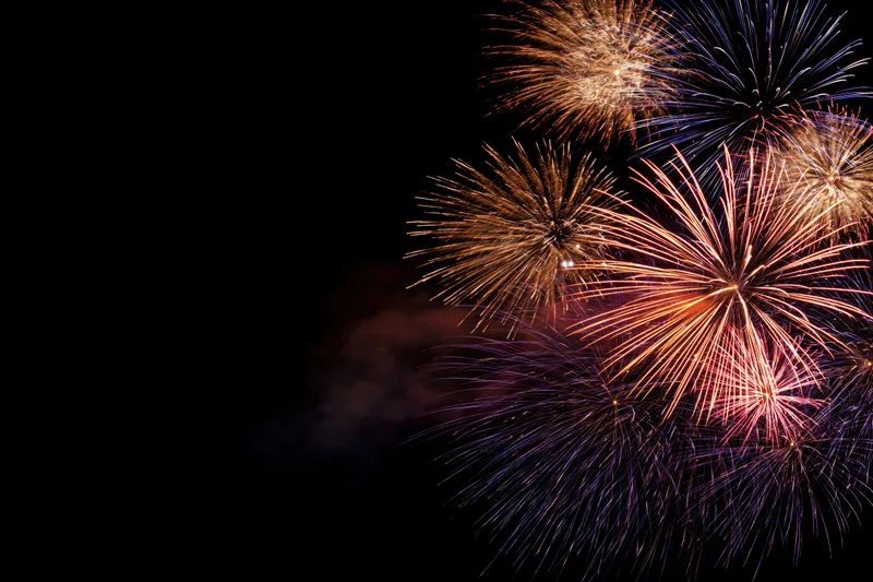 Fireworks bursting in the night sky with vibrant colors and smoke trails