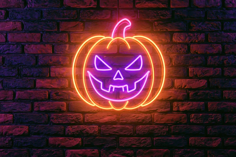 Neon jack-o-lantern sign glowing on dark brick wall