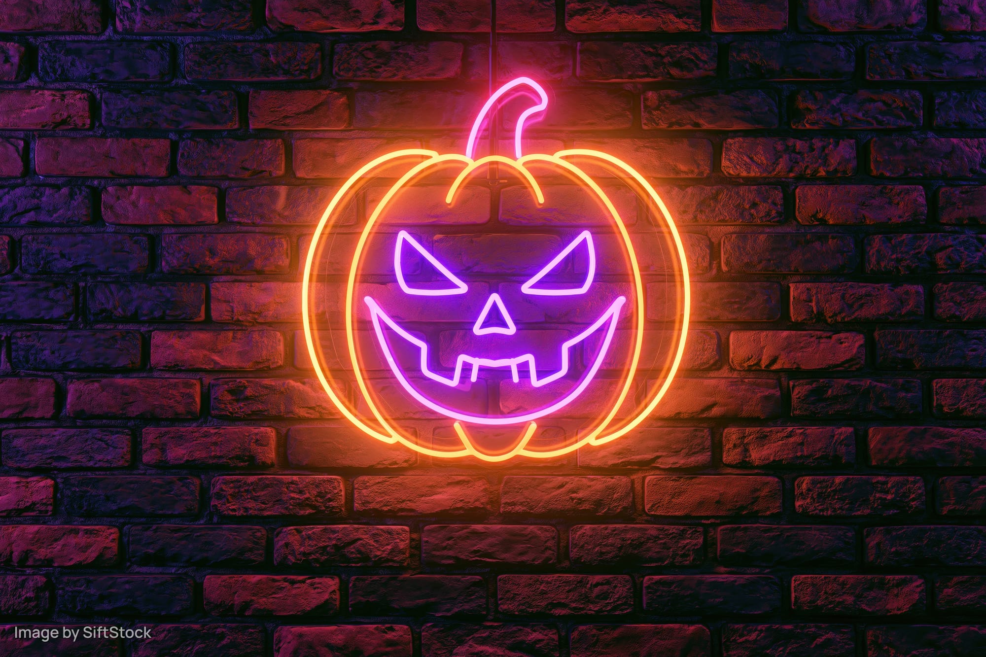 Neon jack-o-lantern sign glowing on dark brick wall
