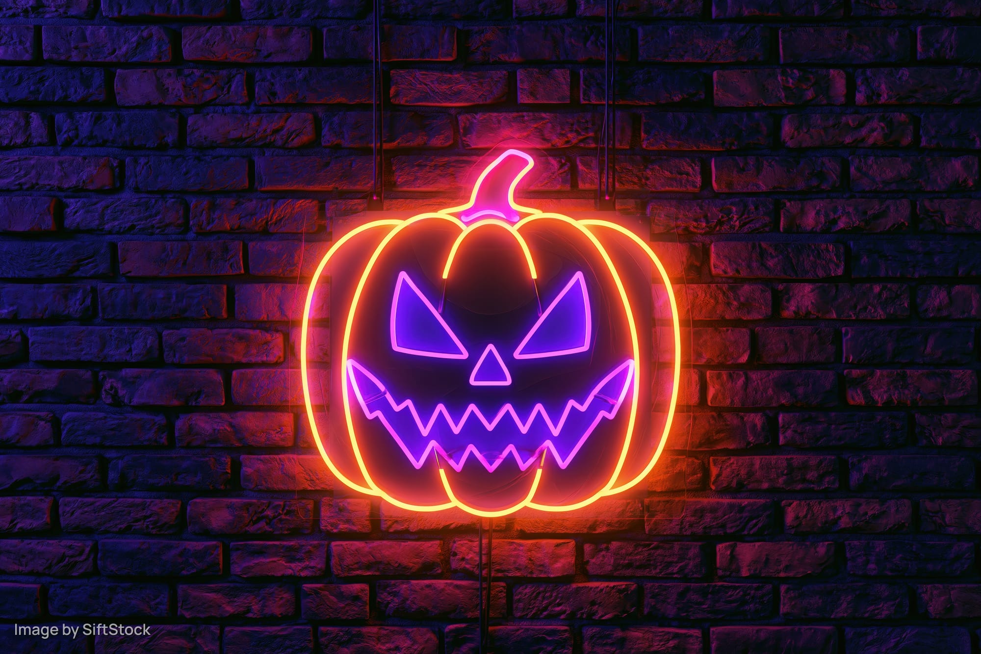 Neon jack-o-lantern sign glowing on dark brick wall