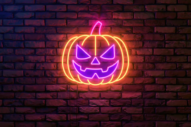 Neon jack-o-lantern sign glowing on dark brick wall