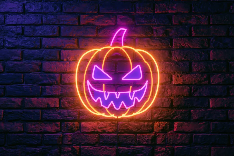Neon jack-o-lantern sign glowing on dark brick wall