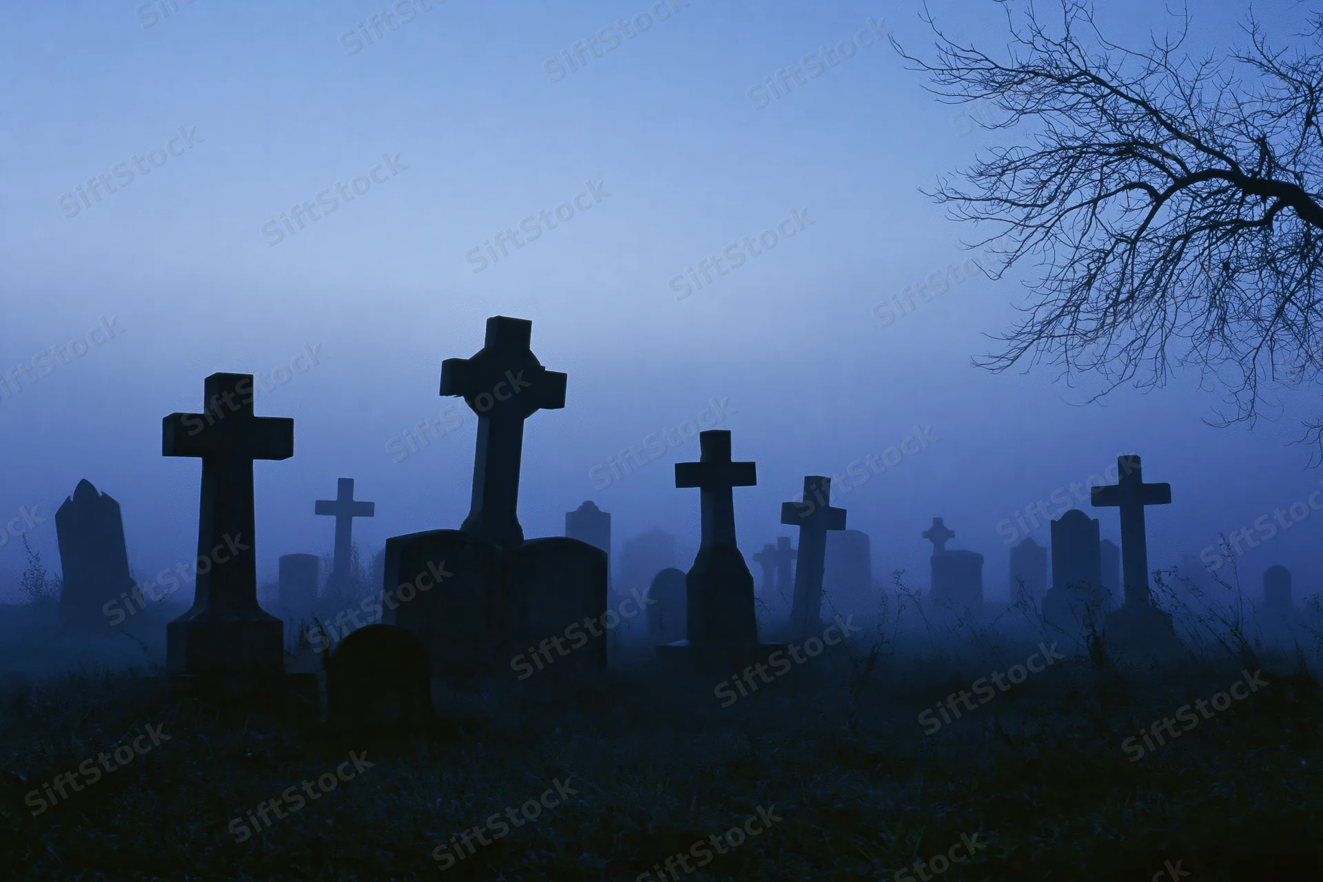 Silhouetted stone crosses and grave markers in a misty old cemetery at twilight