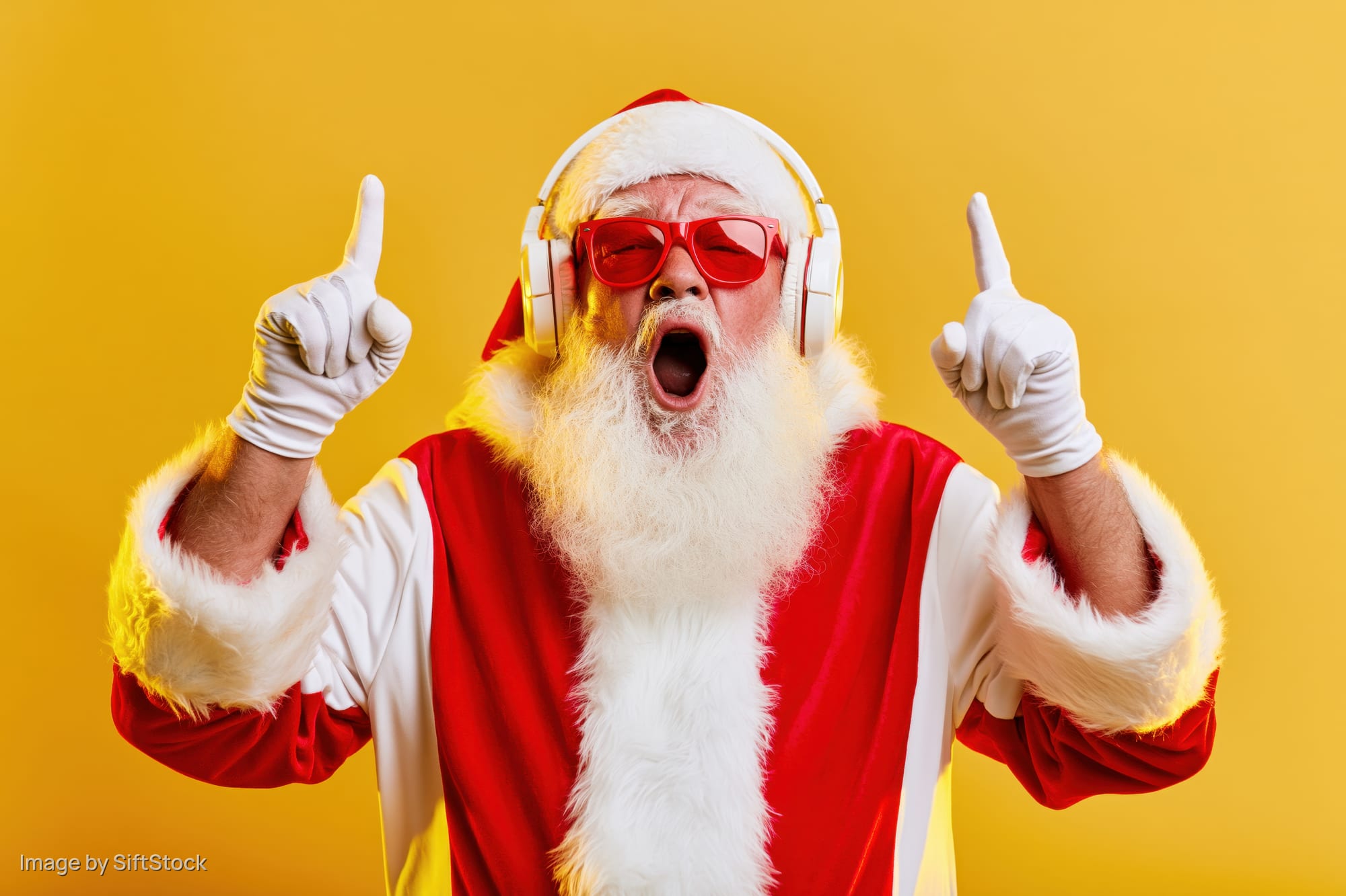 Santa claus in red suit and white fur trim wearing red sunglasses and white headphones, pointing upward with both hands while singing with mouth open against yellow background