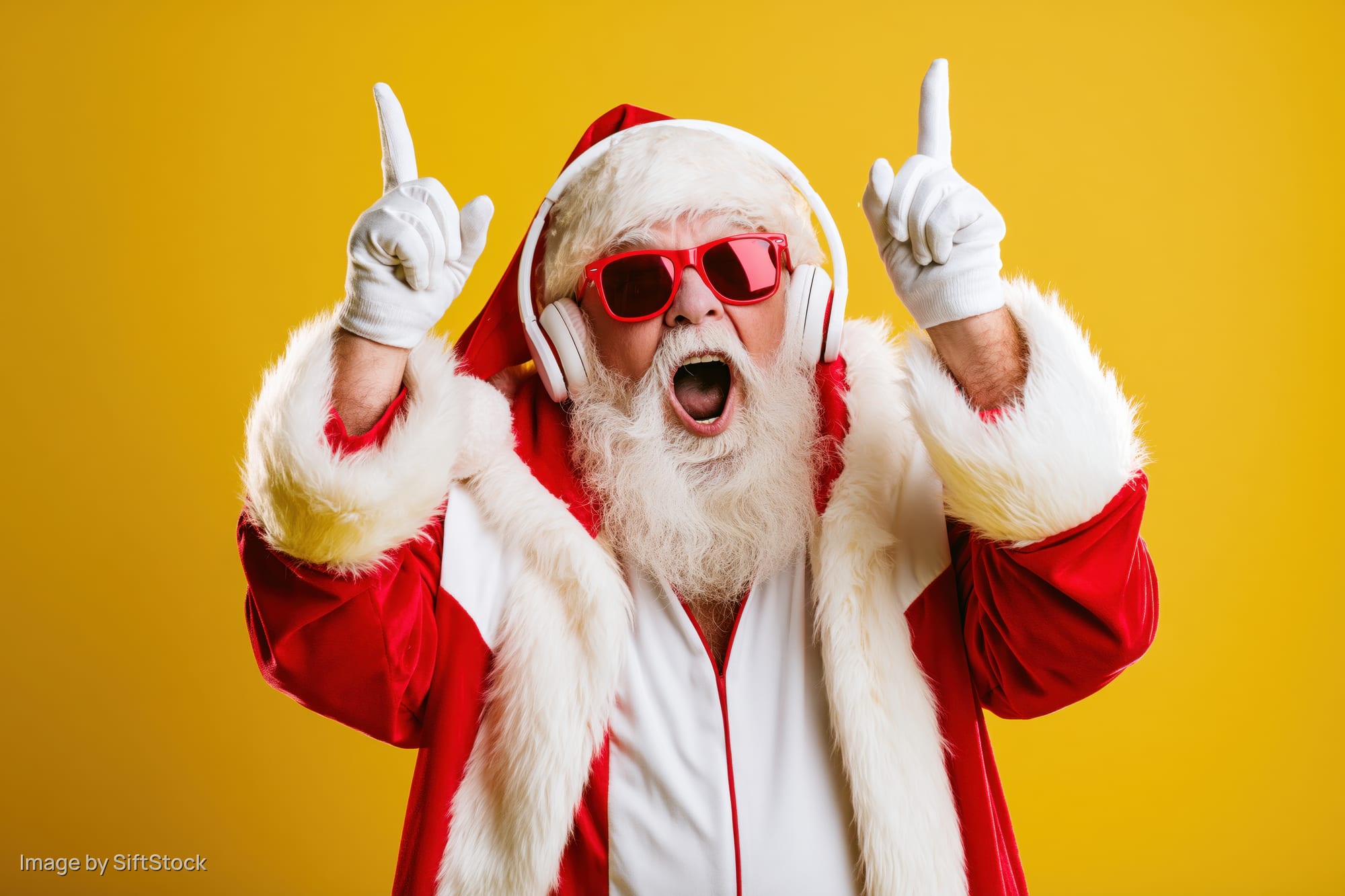 Santa claus in red suit and sunglasses pointing upward with headphones on yellow background