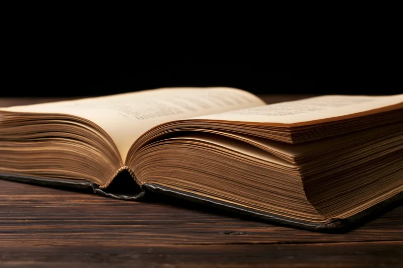 Open weathered hardcover book lying flat on dark wooden table