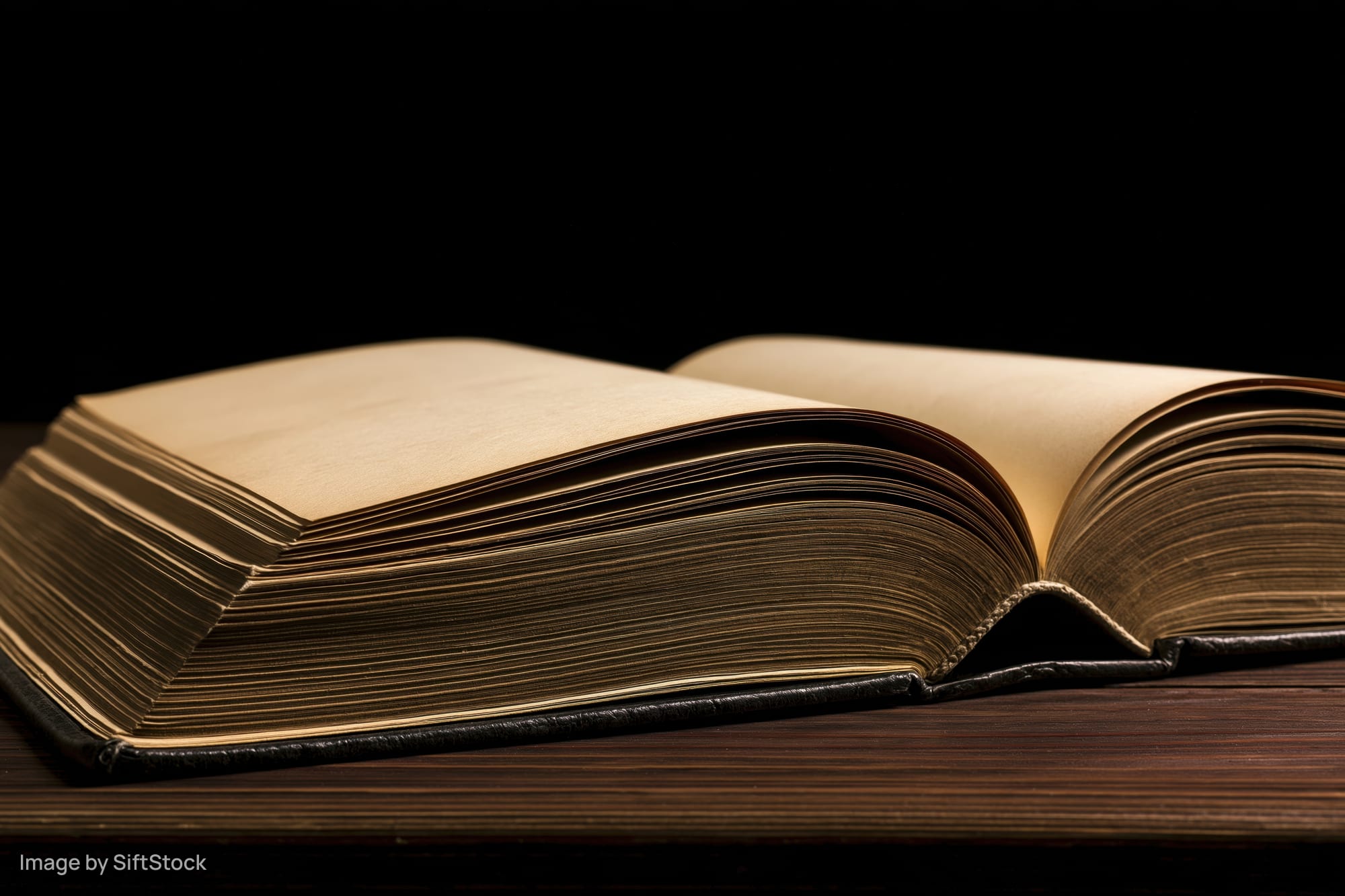 Open weathered hardcover book lying flat on dark wooden table