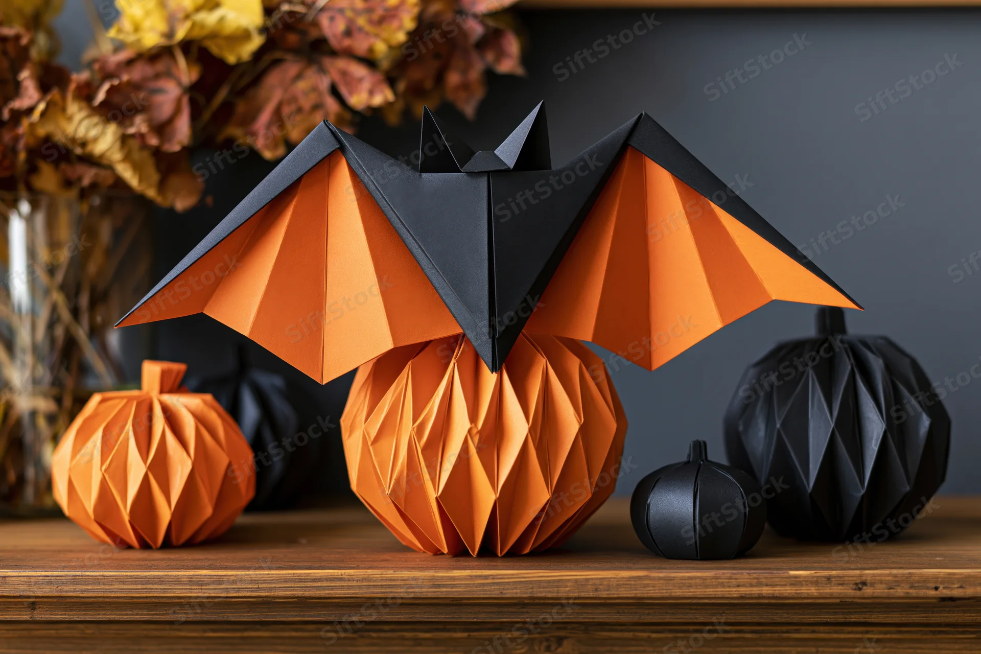 Origami bat and pumpkins arranged on a wooden shelf for halloween decoration