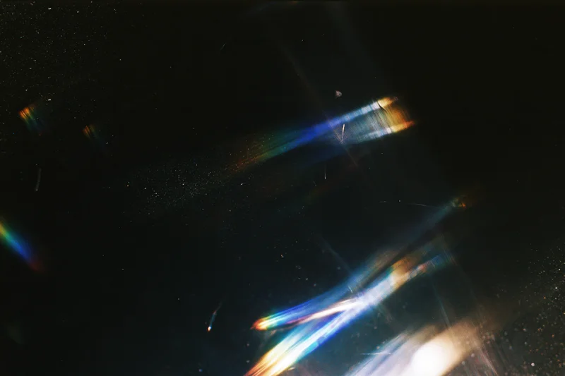 Colorful light streaks and lens flares scattered across a dark background