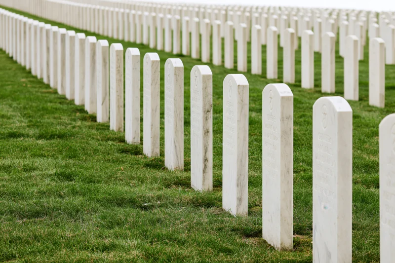 Rows of white marble military headstones aligned in neat rows across a green lawn in a national cemetery