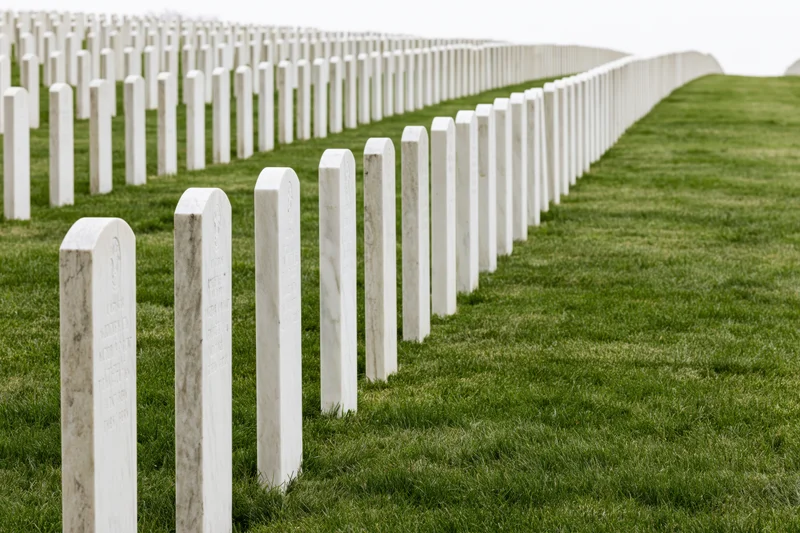 Rows of white marble military headstones aligned in neat rows across a green lawn