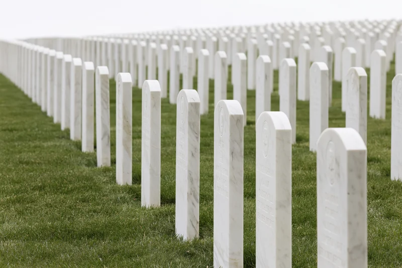 Rows of white marble military headstones aligned in neat rows across a green lawn in a national cemetery