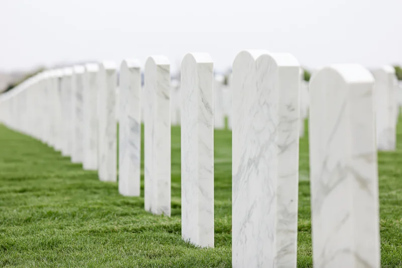 Rows of white marble military headstones aligned in a grassy cemetery field