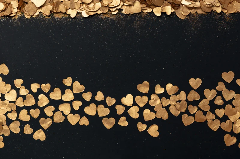 Gold metallic heart confetti arranged in dense horizontal bands along top and bottom of black background