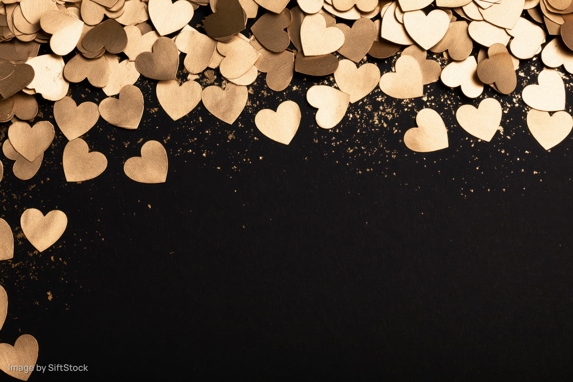 Gold metallic heart confetti scattered densely along the top edge of a black background with copyspace below