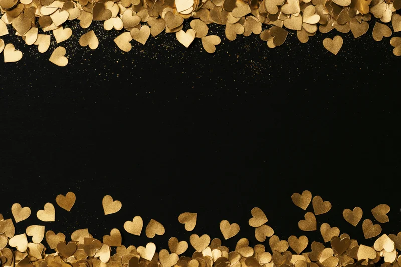 Gold metallic heart confetti arranged along top and bottom edges on black background with central copyspace