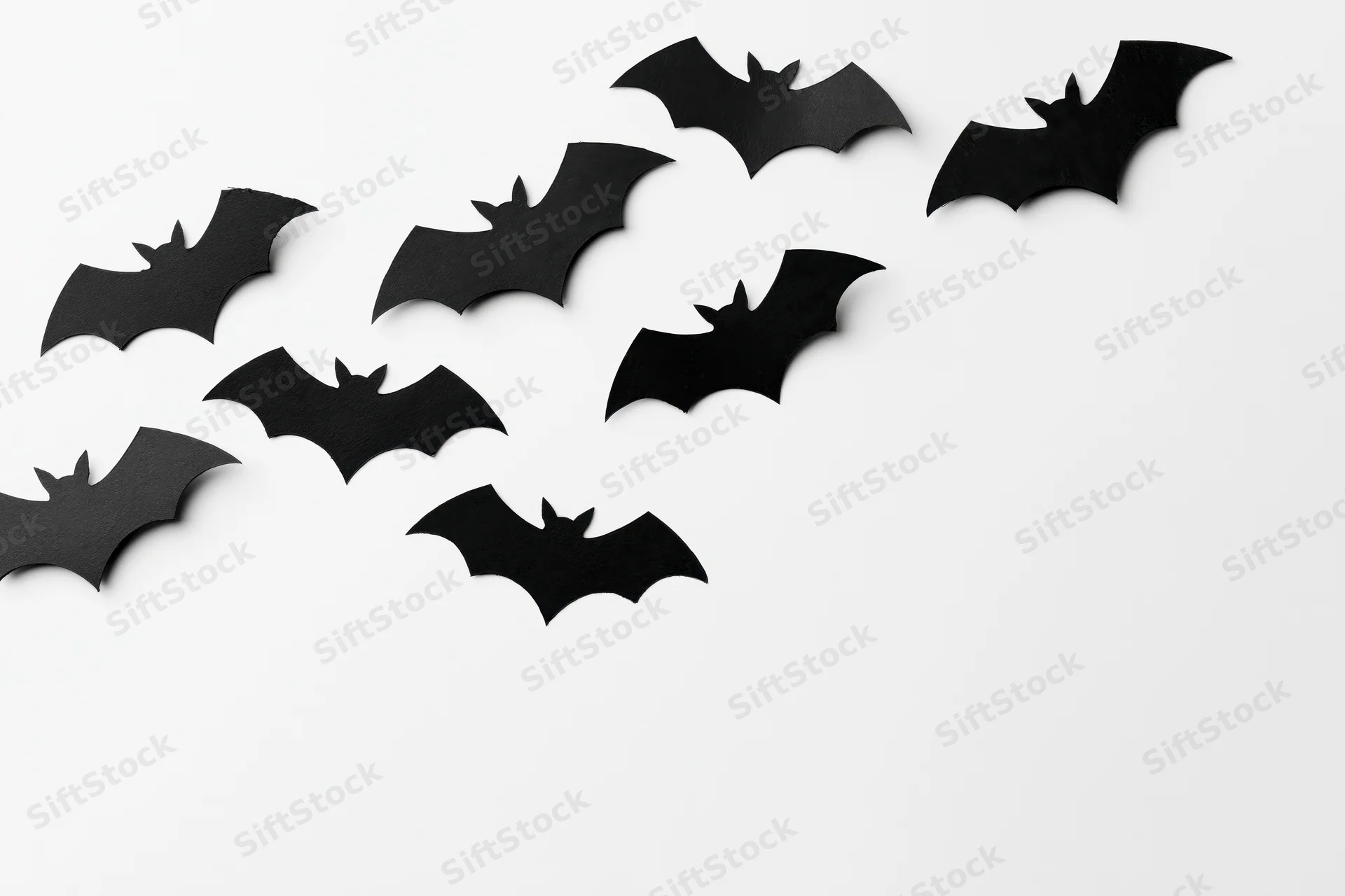 Black paper bat cutouts arranged diagonally on white background