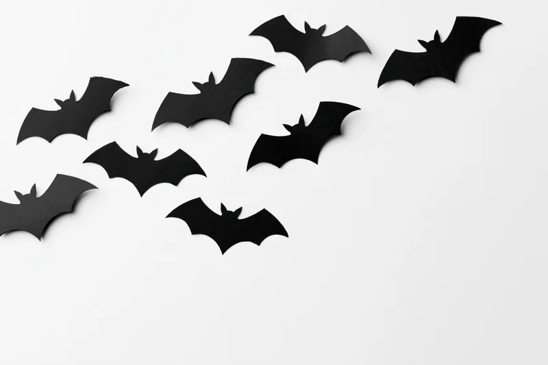 Black paper bat cutouts arranged diagonally on white background