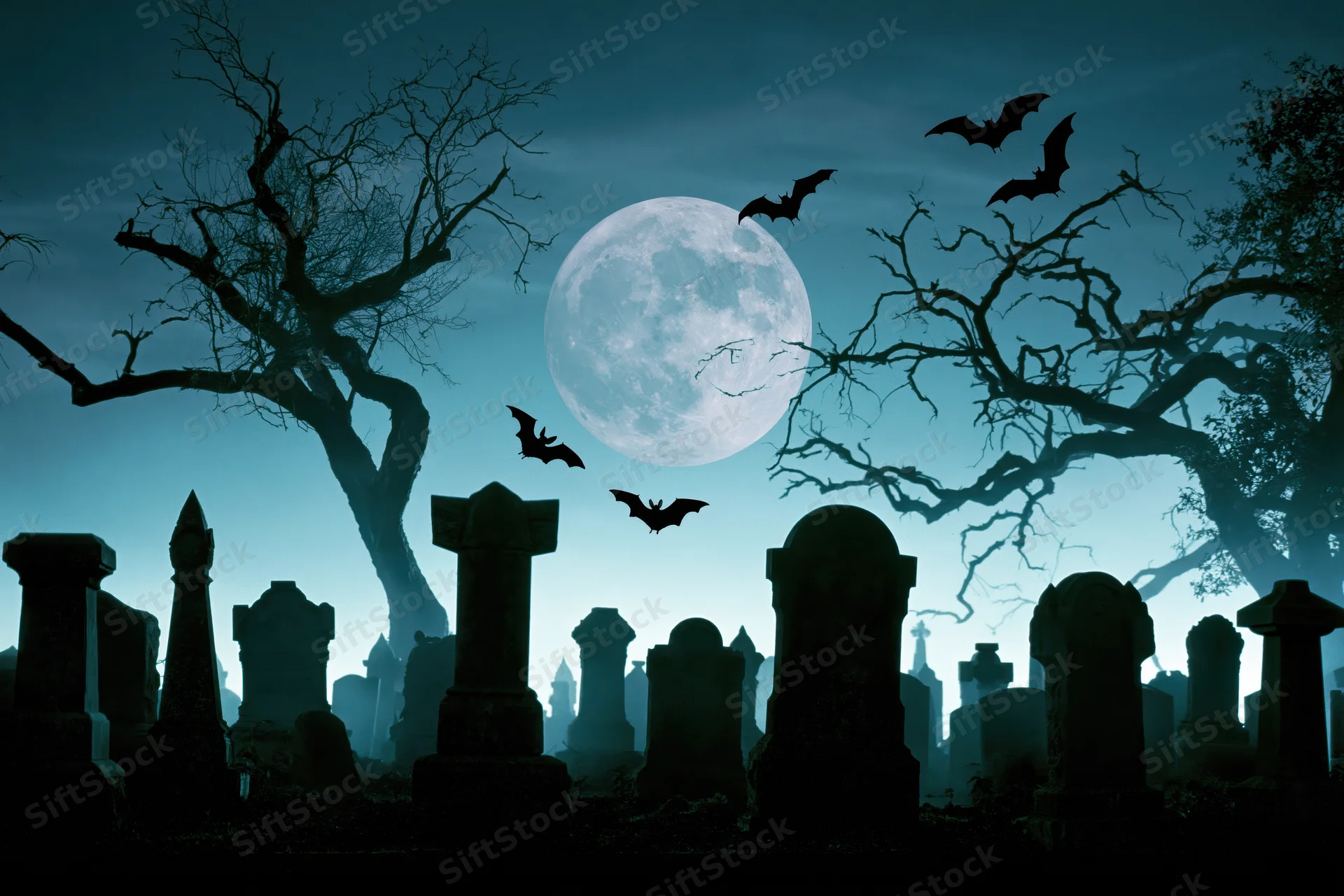 Silhouetted gravestones and bare trees in a cemetery at night under a full moon with bats flying overhead