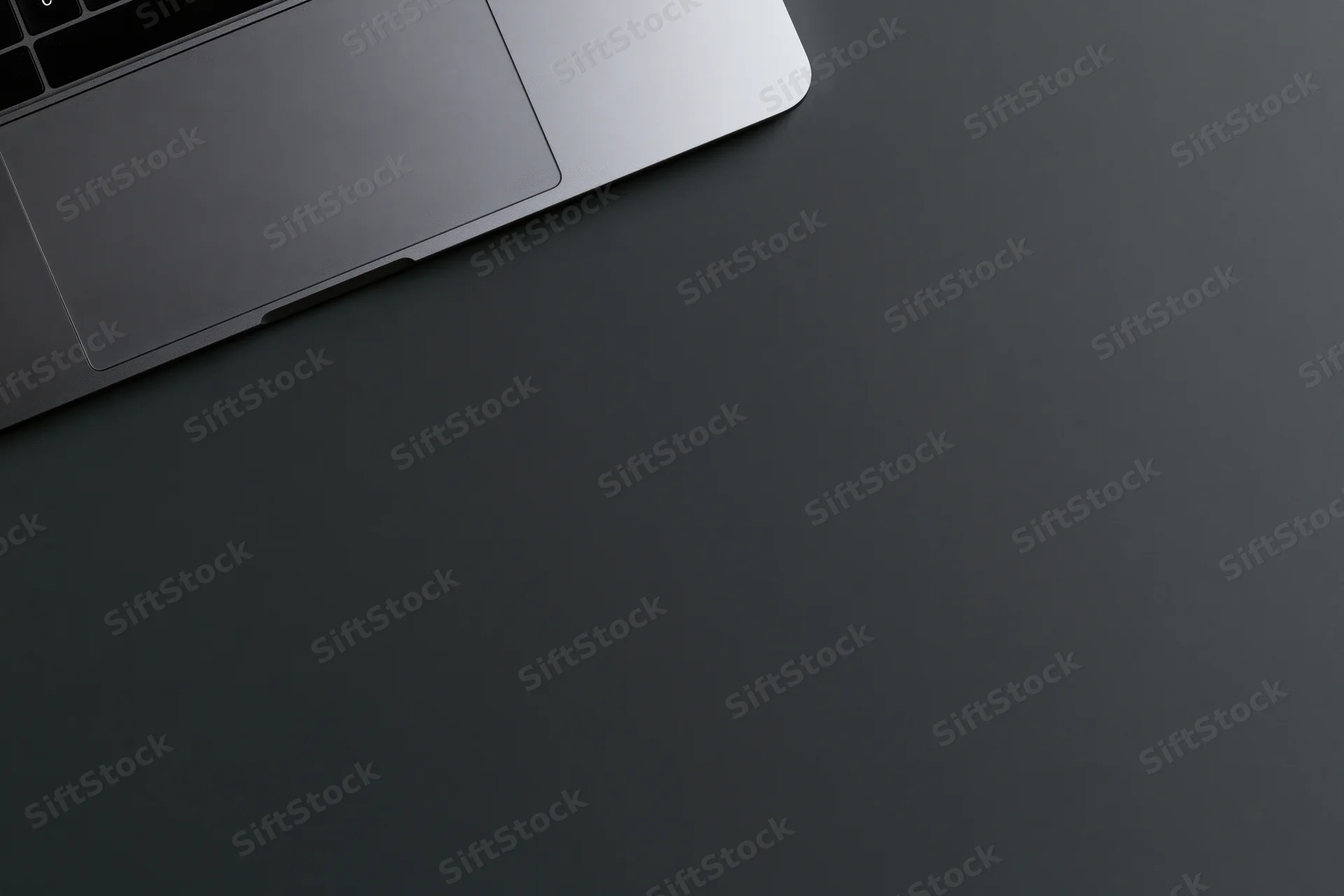Silver aluminum laptop partially visible on dark surface with copyspace