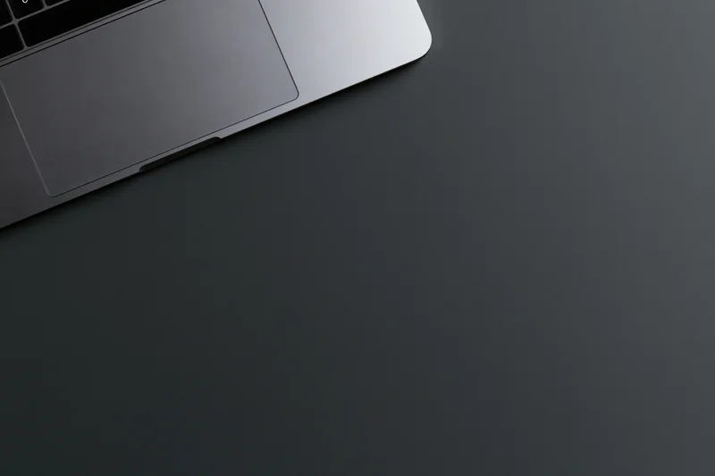 Silver aluminum laptop partially visible on dark surface with copyspace