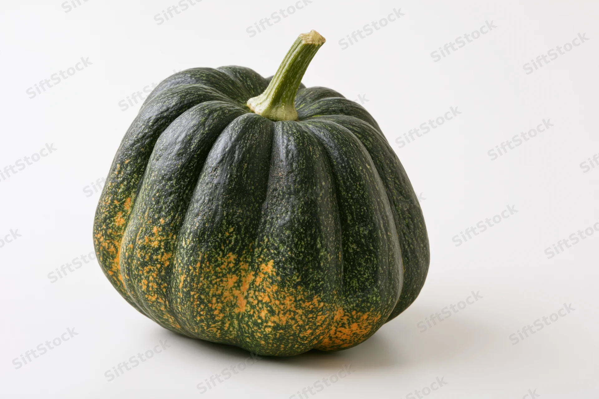 Acorn squash with green and orange skin resting on a white surface