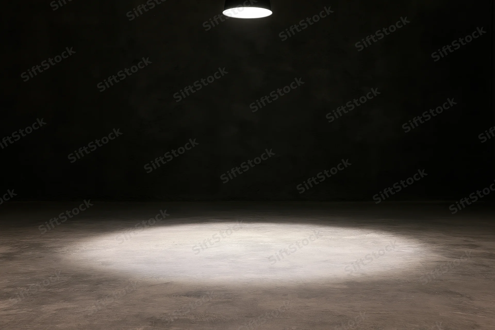 Single overhead spotlight casting a narrow beam of white light on a concrete floor in a dark room