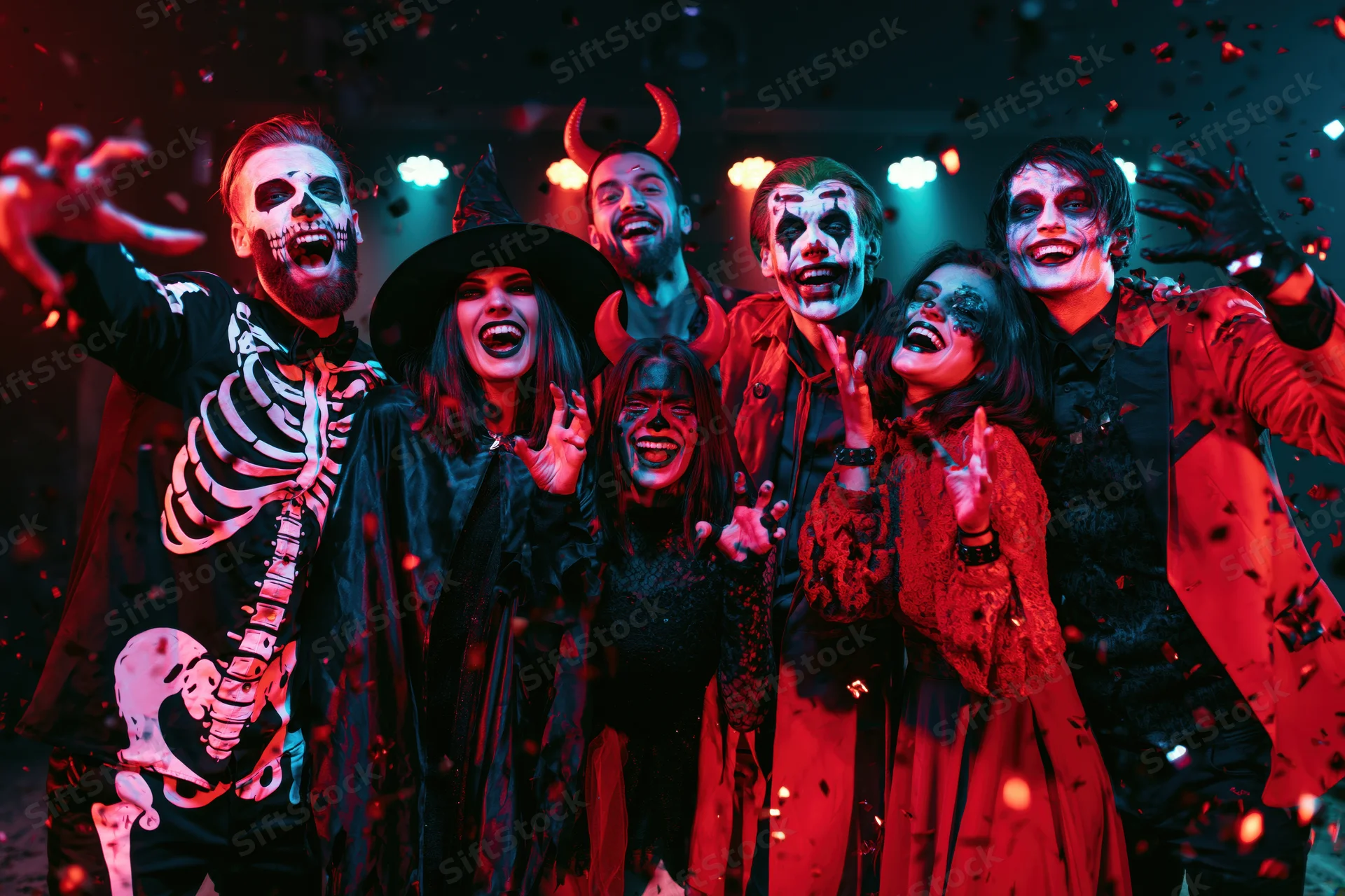Six young adults in halloween costumes laughing and posing at a party