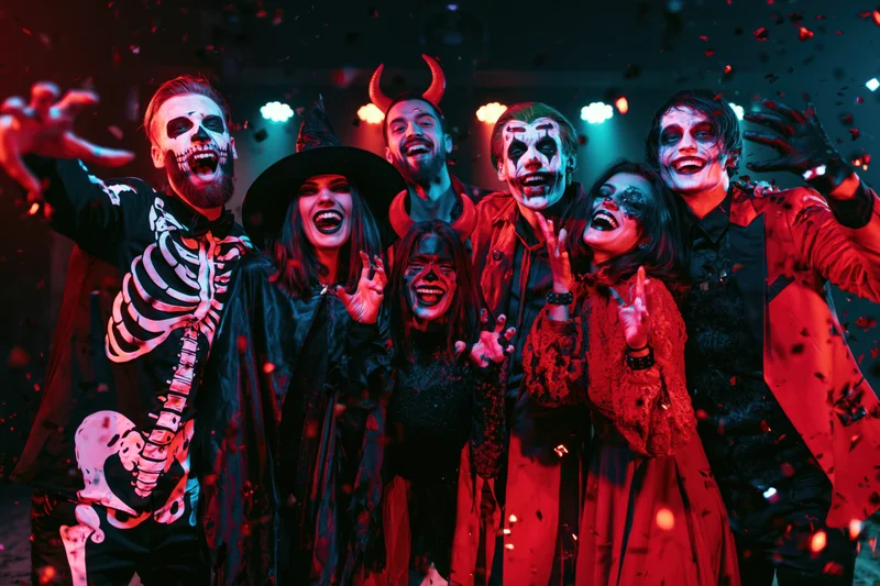Six young adults in halloween costumes laughing and posing at a party