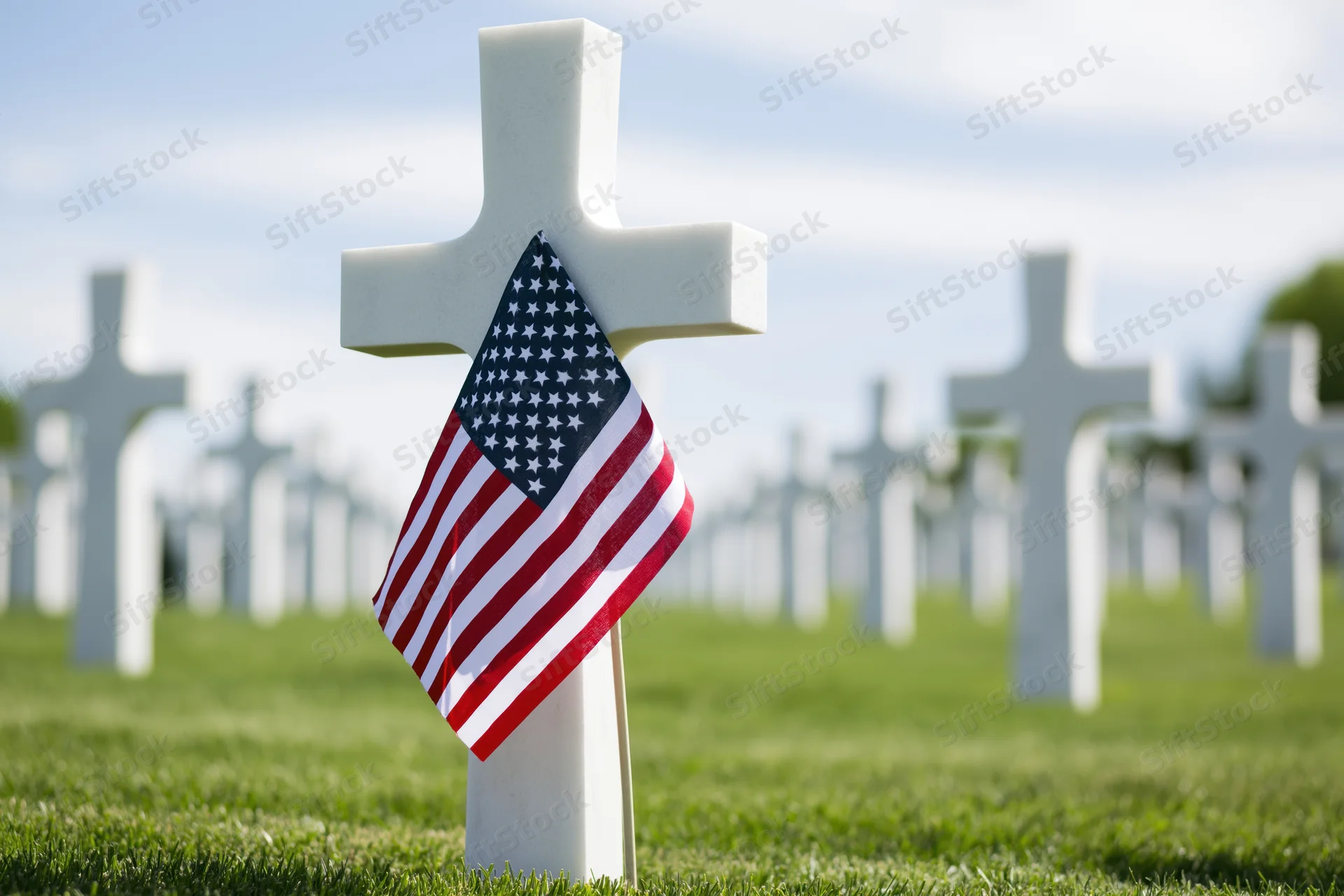 White cross grave marker with small american flag in a military cemetery