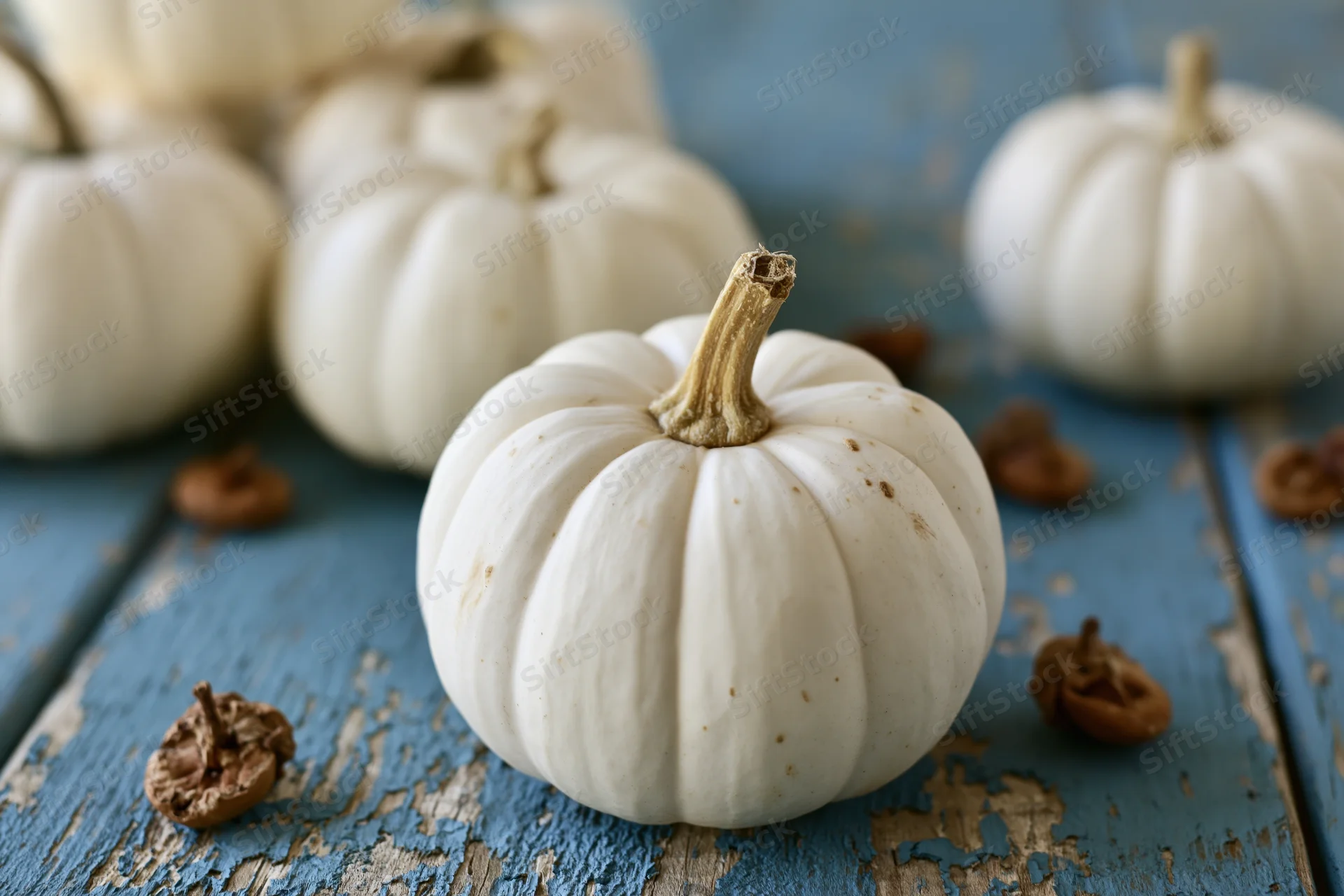 Small white ghost pumpkins arranged on a weathered blue painted wooden table