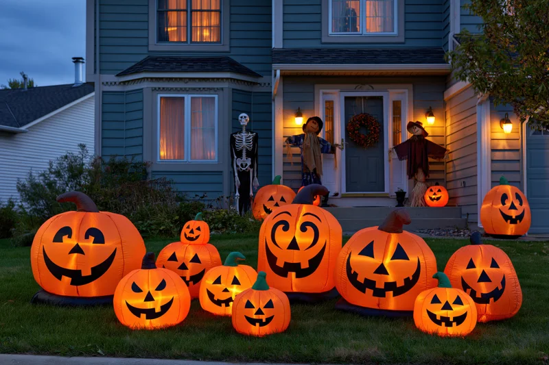 Inflatable jack-o-lanterns and Halloween decorations arranged on a suburban house front yard at dusk