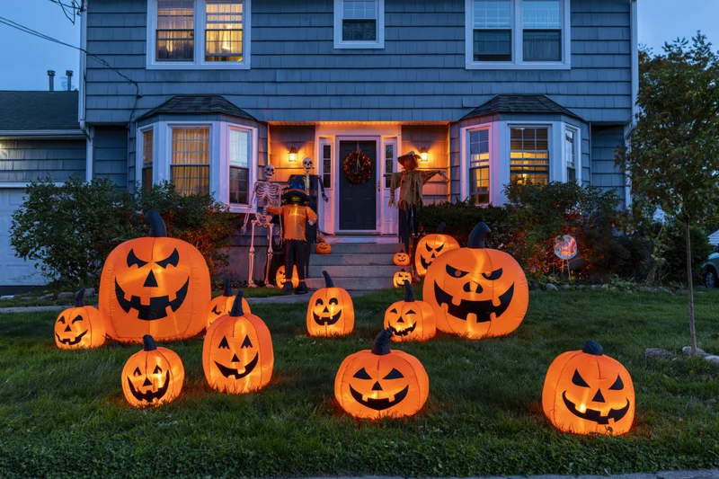 Illuminated pumpkins and halloween decorations in front yard of suburban house at dusk