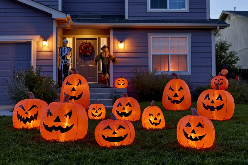 Inflatable pumpkins glowing on a suburban house lawn at dusk with porch decorations