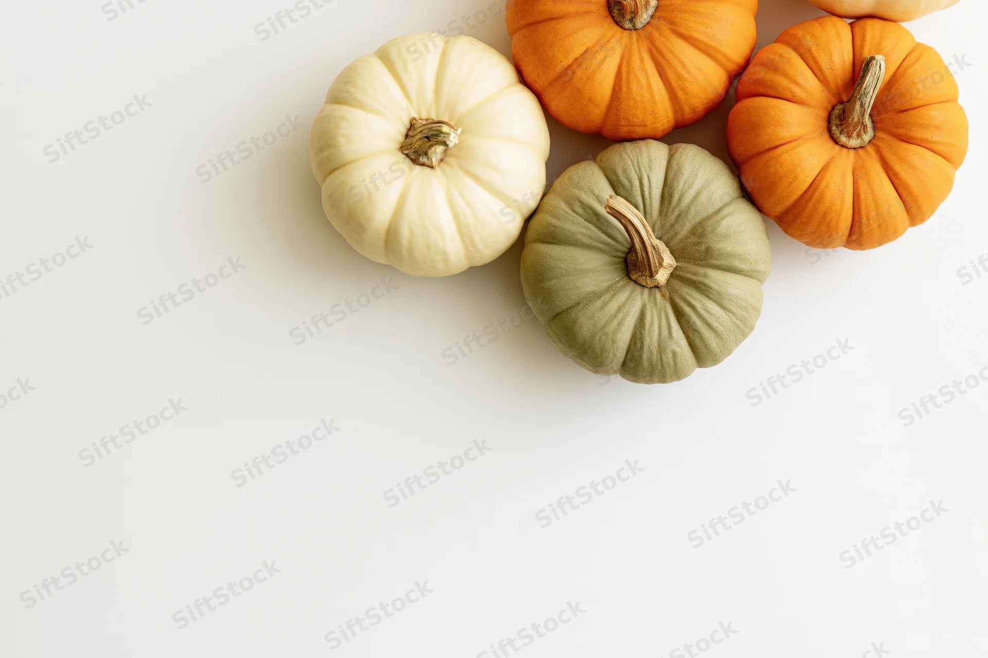 Small decorative pumpkins arranged in upper right corner on white surface