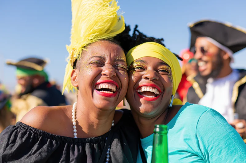Two black brazilian women laughing in carnival costumes at outdoor festival