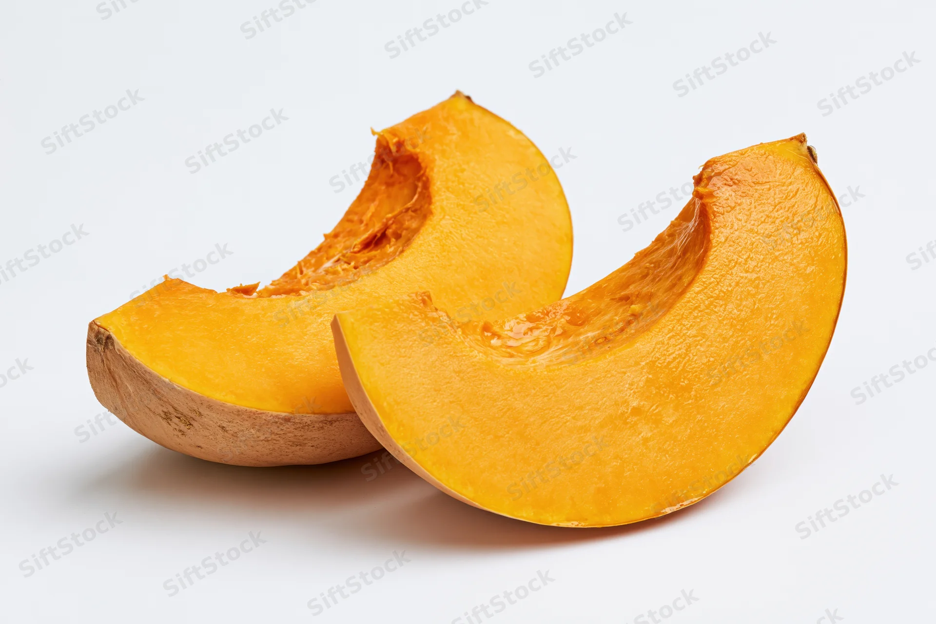 Two curved slices of fresh pumpkin cut and separated on a white background