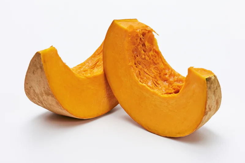 Two curved slices of fresh pumpkin cut and separated on white background