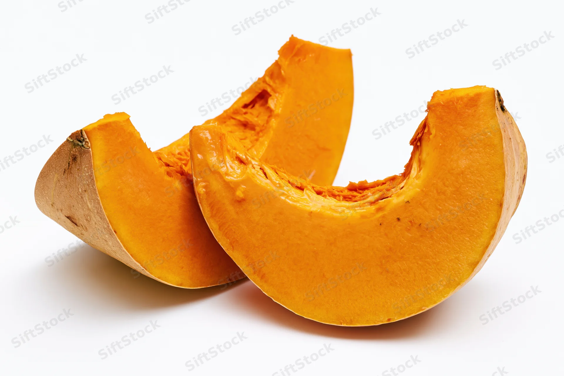 Two curved slices of fresh pumpkin cut and separated on white background