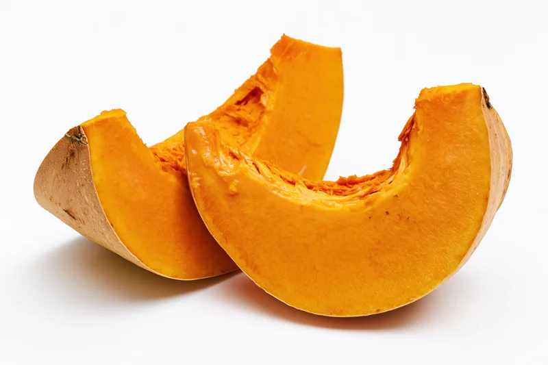 Two curved slices of fresh pumpkin cut and separated on white background