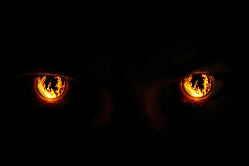 Glowing amber-orange eyes with fiery pupils in complete darkness