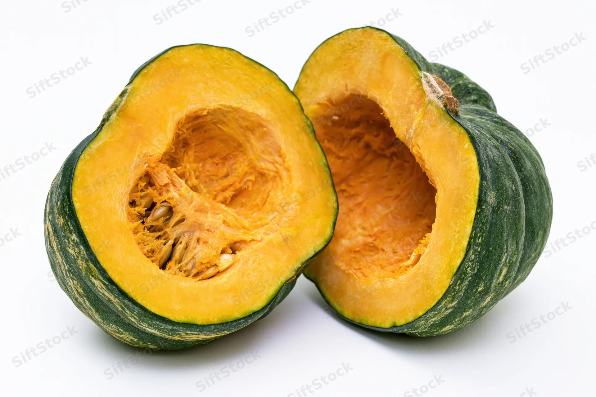 Two halves of a kabocha squash cut open showing orange flesh and seeds on white background