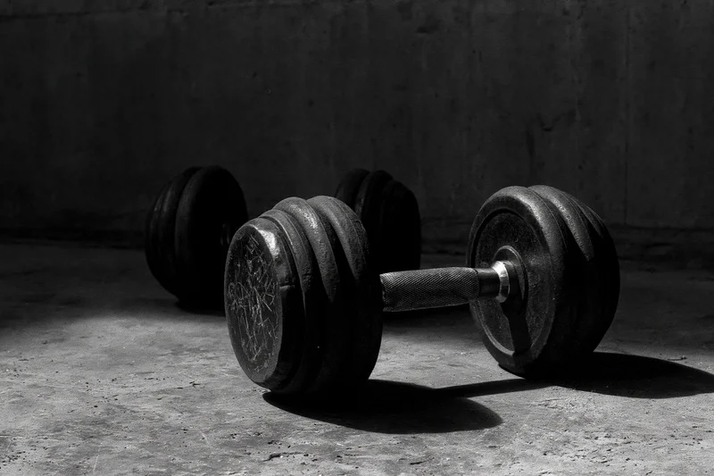 Two iron dumbbells resting on a rough concrete gym floor