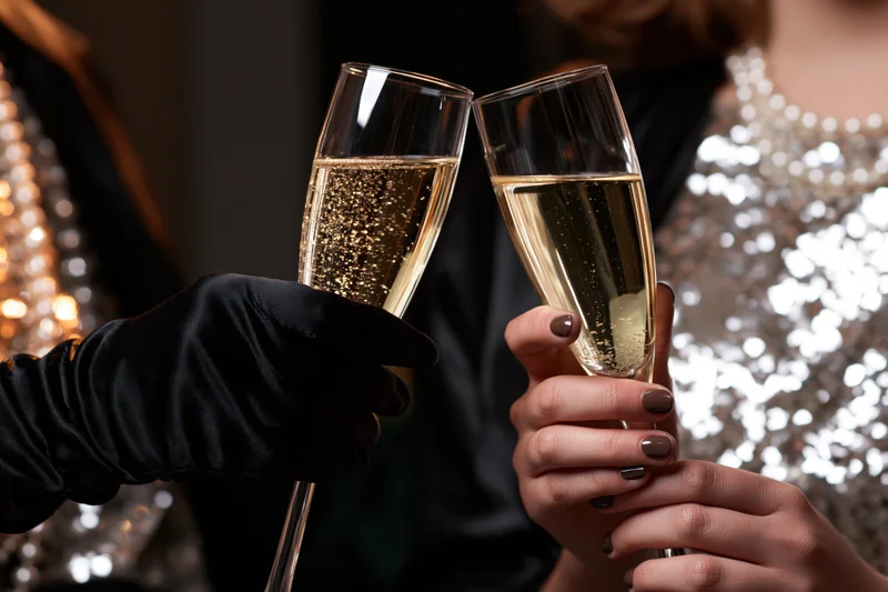 Two women clinking champagne flutes at a glamorous party