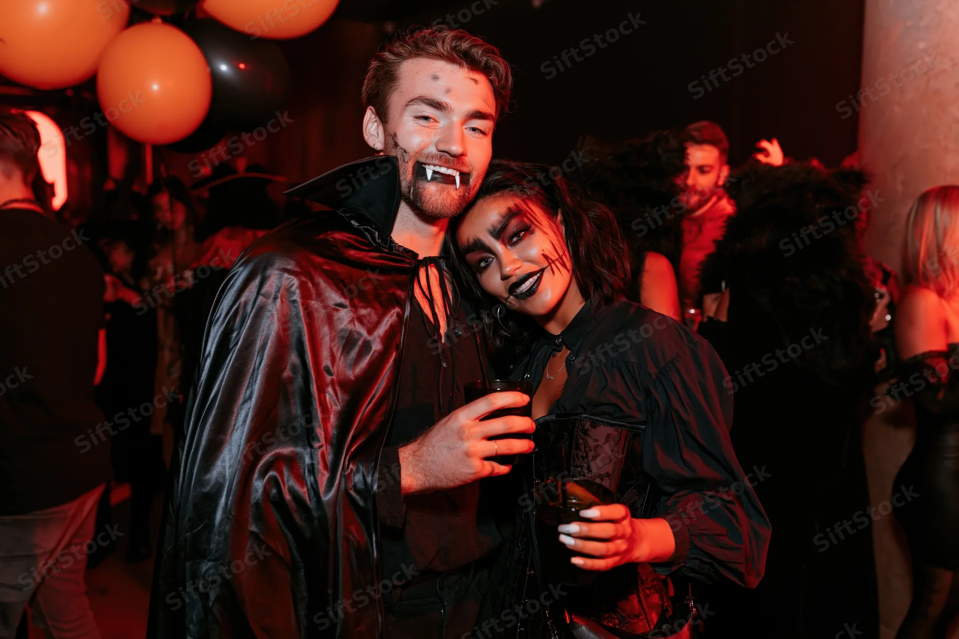 Couple in vampire costumes posing together at a halloween party in a nightclub
